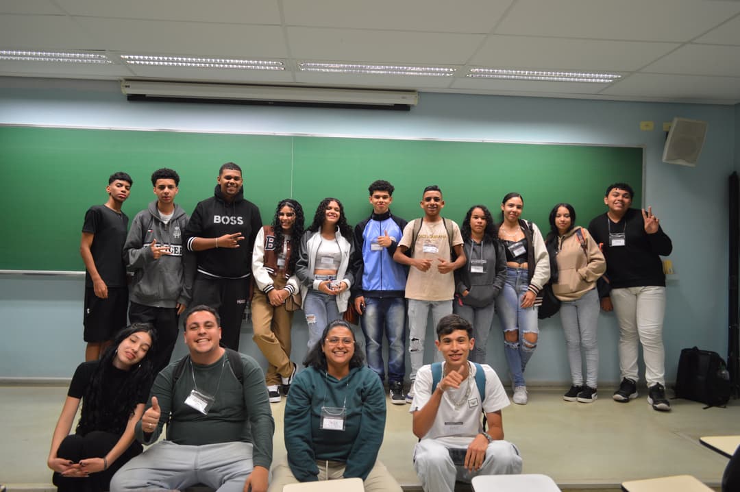 Foto de alunos do ensino médio. Temos a maioria deles próximo à lousa e o resto agachado 